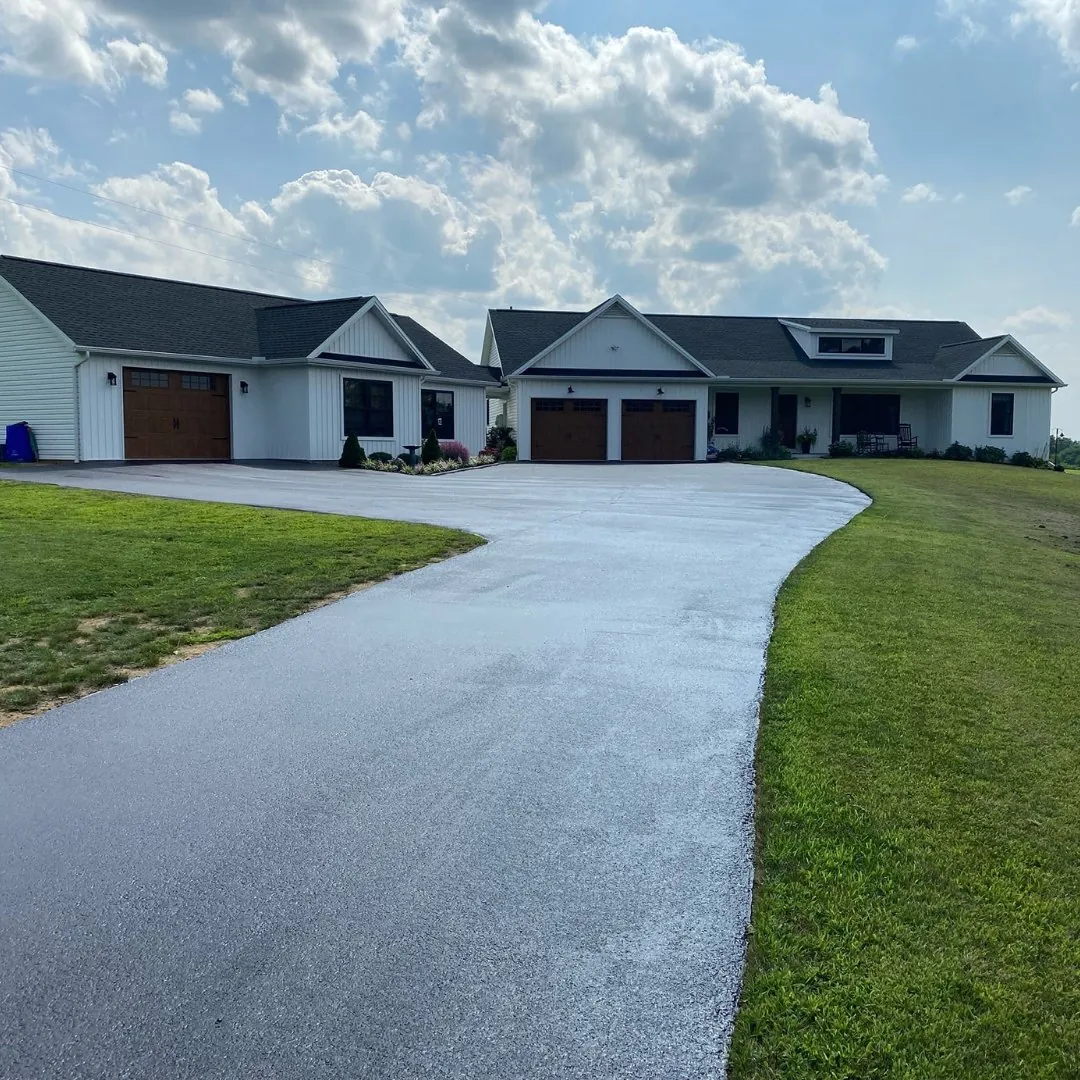 New asphalt driveway curving to a single storey home