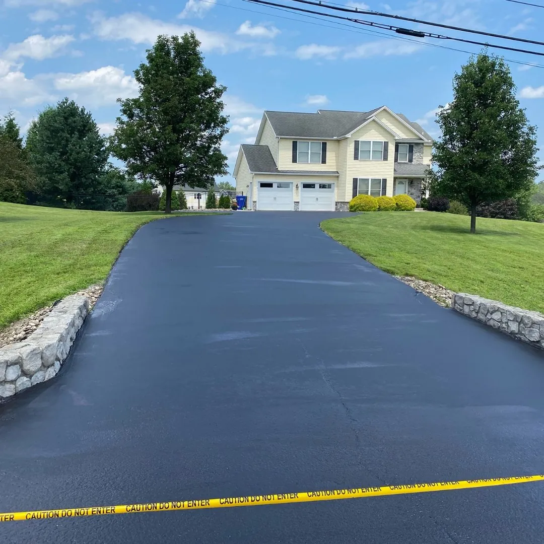 Long asphalt driveway approaching a two storey home