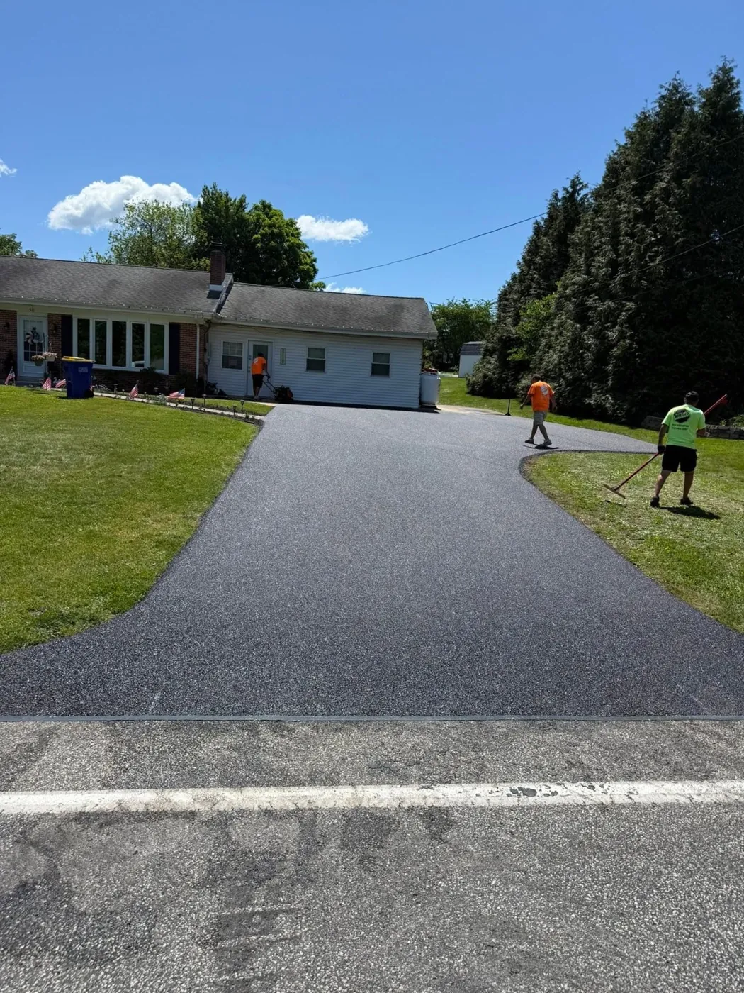 Crew applying seal coat on a residential driveway